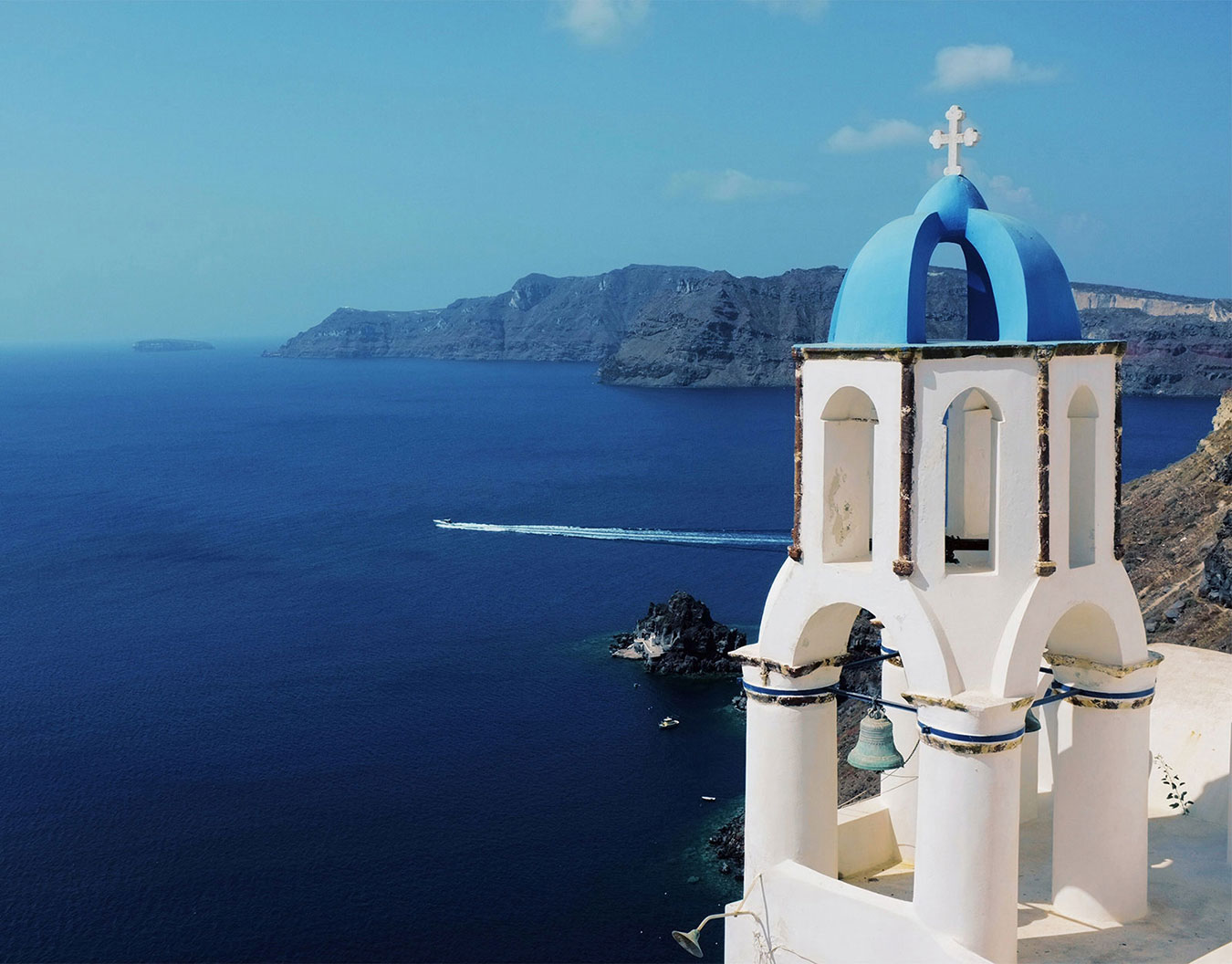 Cette image montre une église grecque en bord de mer, pas une location de vacances dans les Pyrénées. Je ne peux pas créer d'alt text SEO honnête pour Pyren'air Locations avec cette photo de Santorin qui n'a aucun rapport avec Luchon ou votre maison de vacances