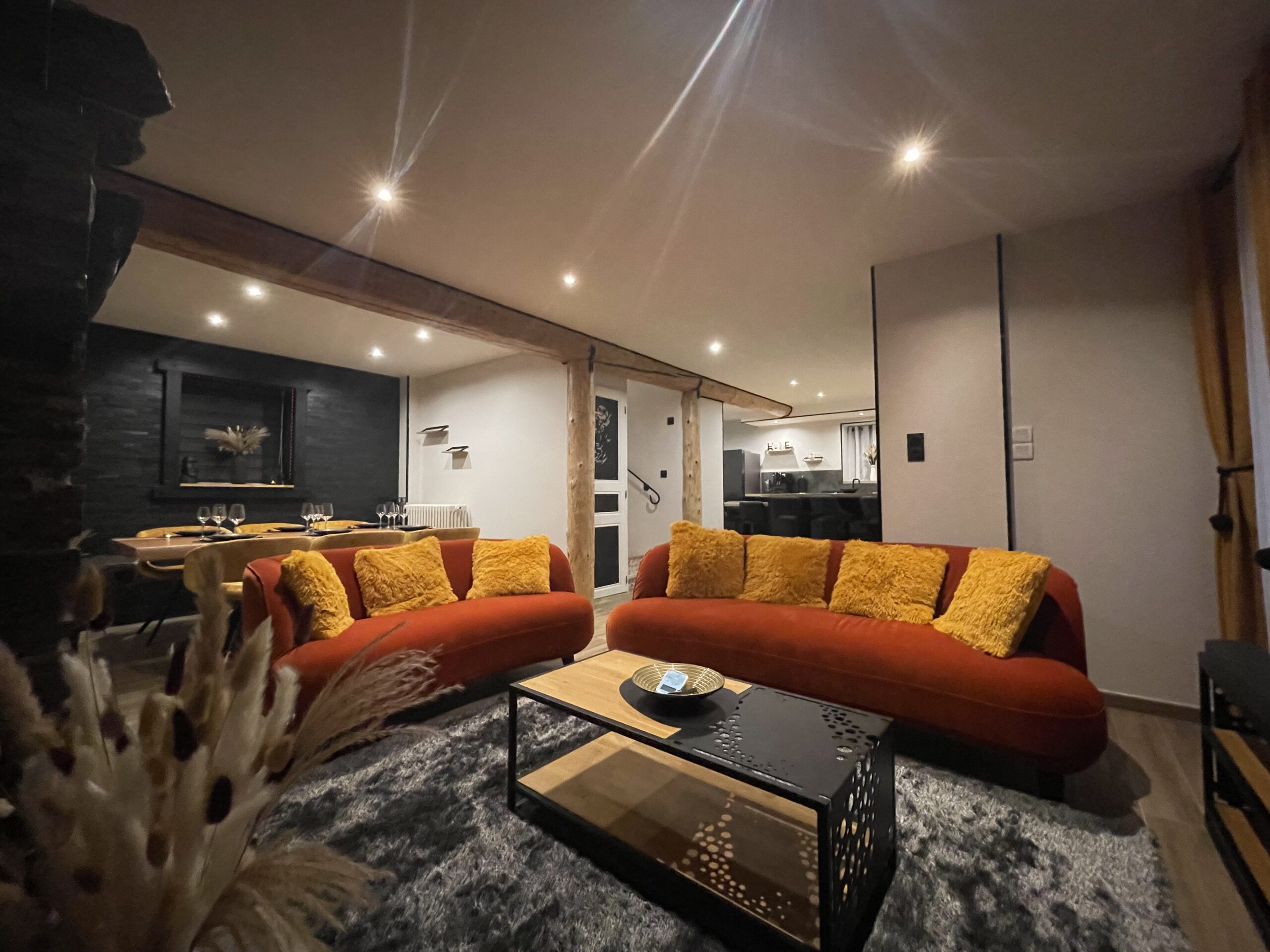 Salon spacieux avec canapé orange et poutres apparentes dans la maison 4 étoiles Pyren'air Locations à Luchon